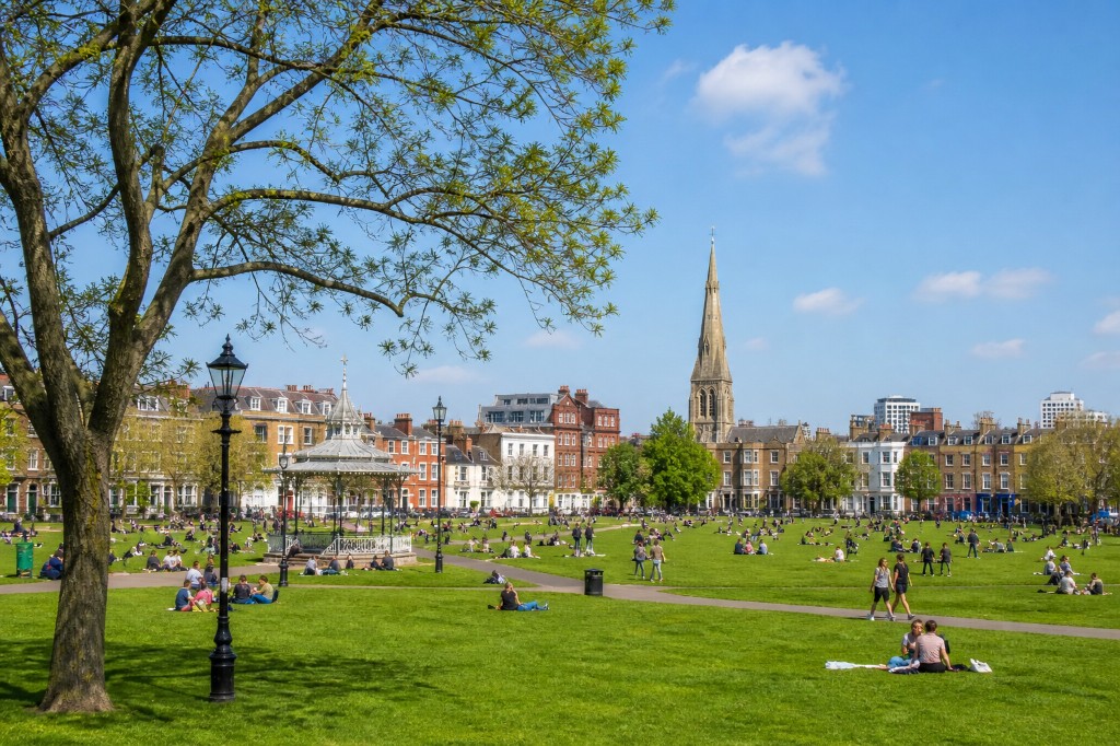 Sunny day at Clapham Common: bandstand, church spire and people on the grass with Victorian terraces behind