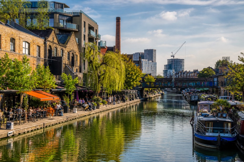 Regent's Canal in East London with narrowboats, caf&eacute;s on the towpath and warehouse buildings